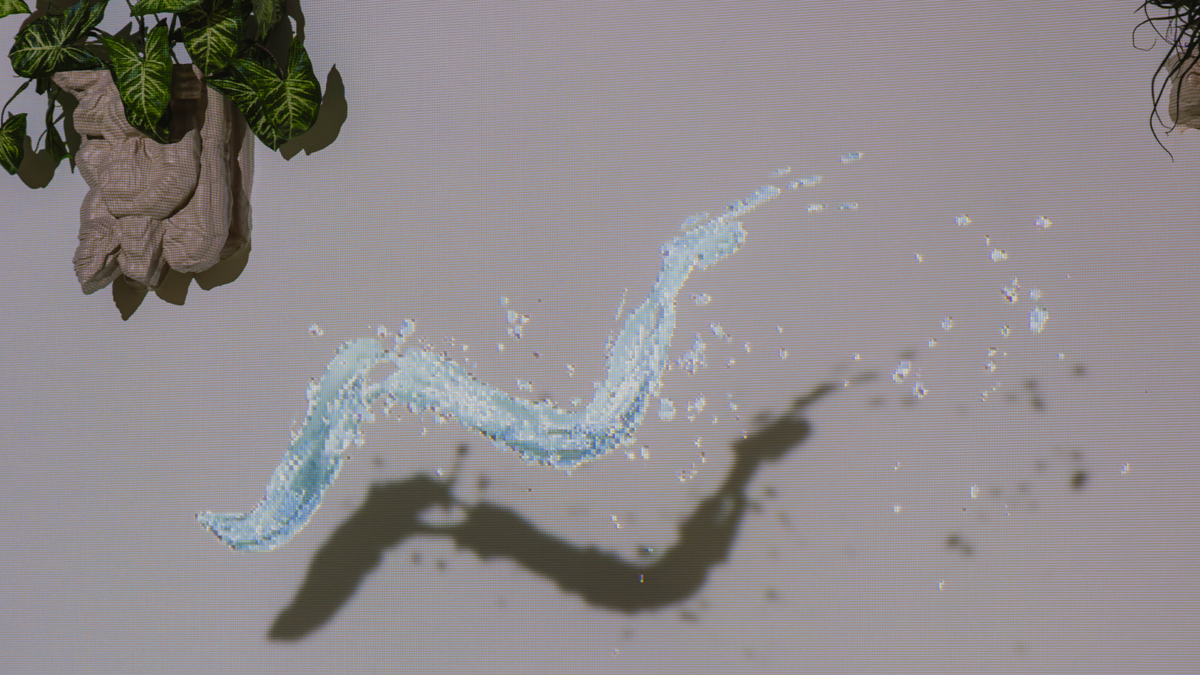 Animierte Wasserstrahlen gleiten spielerisch zwischen skulpturalen Elementen und Pflanzen hinter dem Jungbrunnen hin und her.